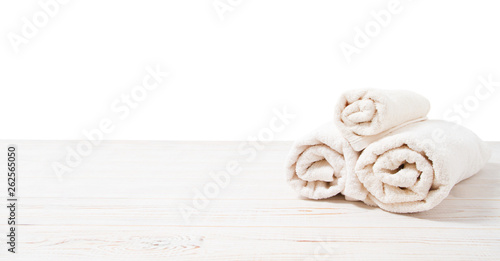 Rolled white towels on white wooden table isolated on white background. Copy space and top view. Bathroom objects for shower body treatment. Selective focus. Banner