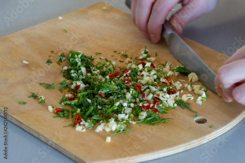 Fresh chopped by knife in female hands spices with garlic, red chilli peppers, green fennel