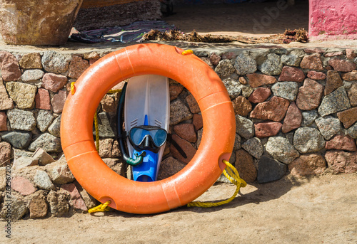 flippers with swimming mask and an orange life preserver against a stone wall in Egypt