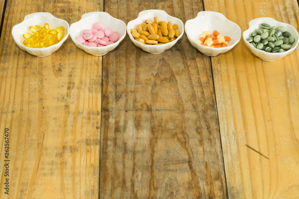 Drugs in the form of capsules, tablets and gelatin in oyster-shaped bowls on dirty wooden background Drugs in the form of capsules, tablets and gelatin in oyster-shaped bowls on dirty wooden background