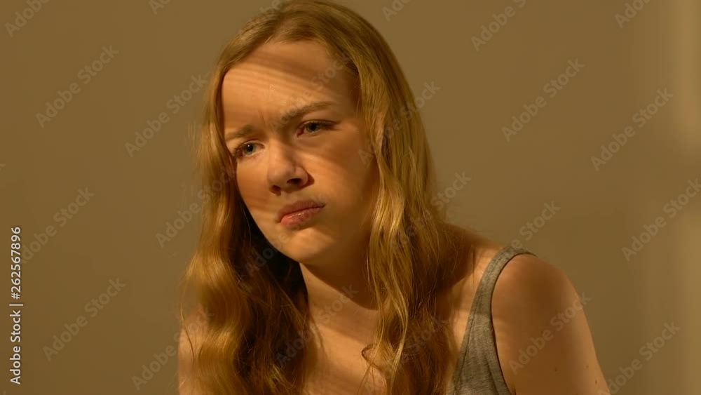 Depressed teenager girl sitting alone in room, awkward age, bullying victim Depressed teenager girl sitting alone in room, awkward age, bullying victim