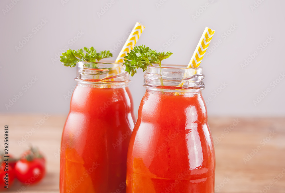 Tomato juice in bottles with parsley and salt on the wooden table Tomato juice in bottles with parsley and salt on the wooden table