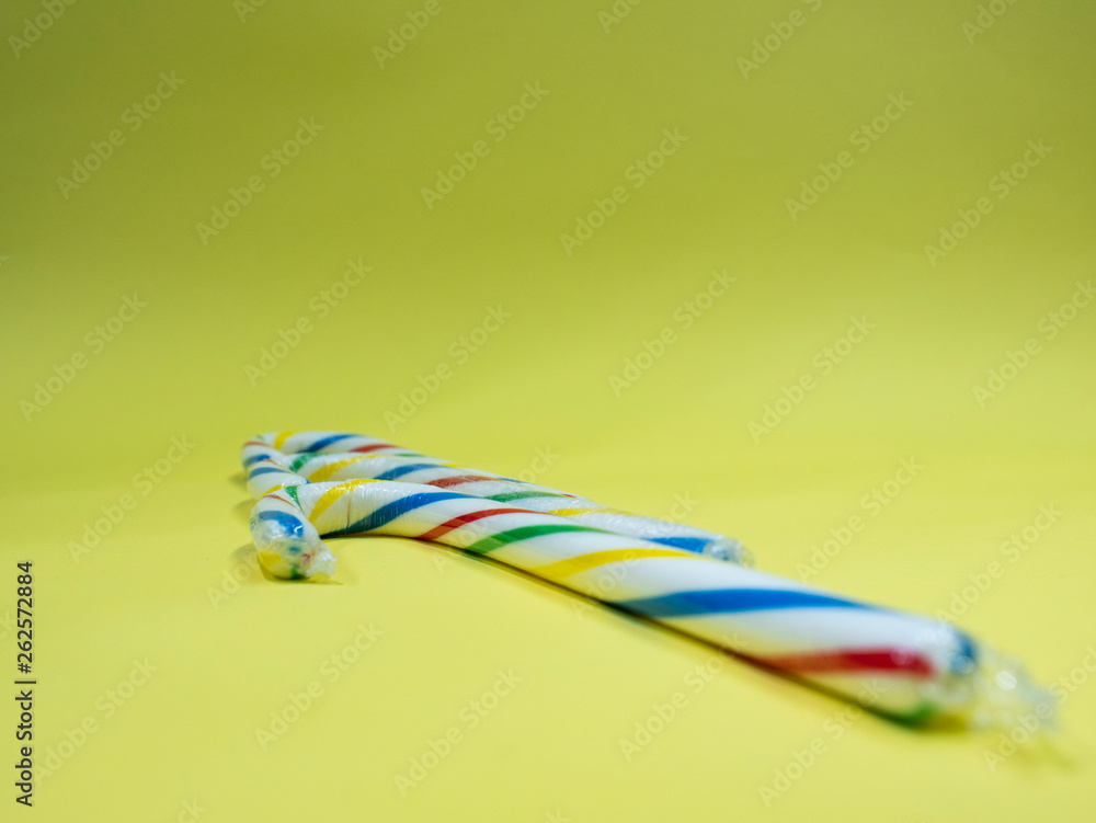 two candy colorful caramel cane on yellow background two candy colorful caramel cane on yellow background