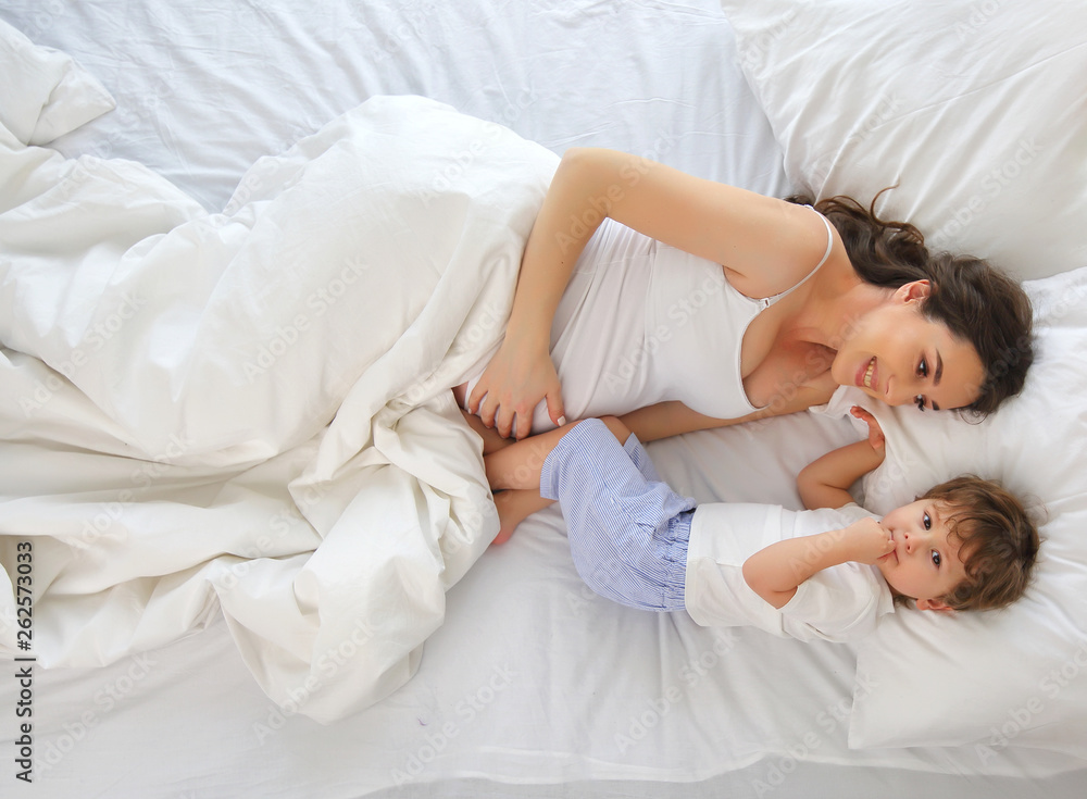 Portrait of a pregnant mother and son on the bed. The view from the top.