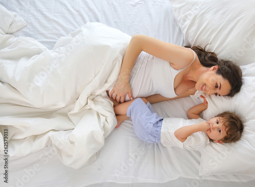 Portrait of a pregnant mother and son on the bed. The view from the top.