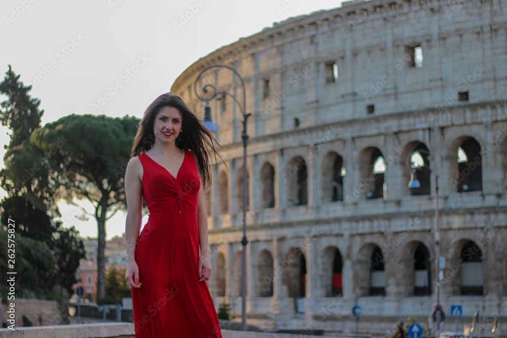 Pretty young girl in red dress in front of Colosseum, Rome, Italy. Rome symbol.