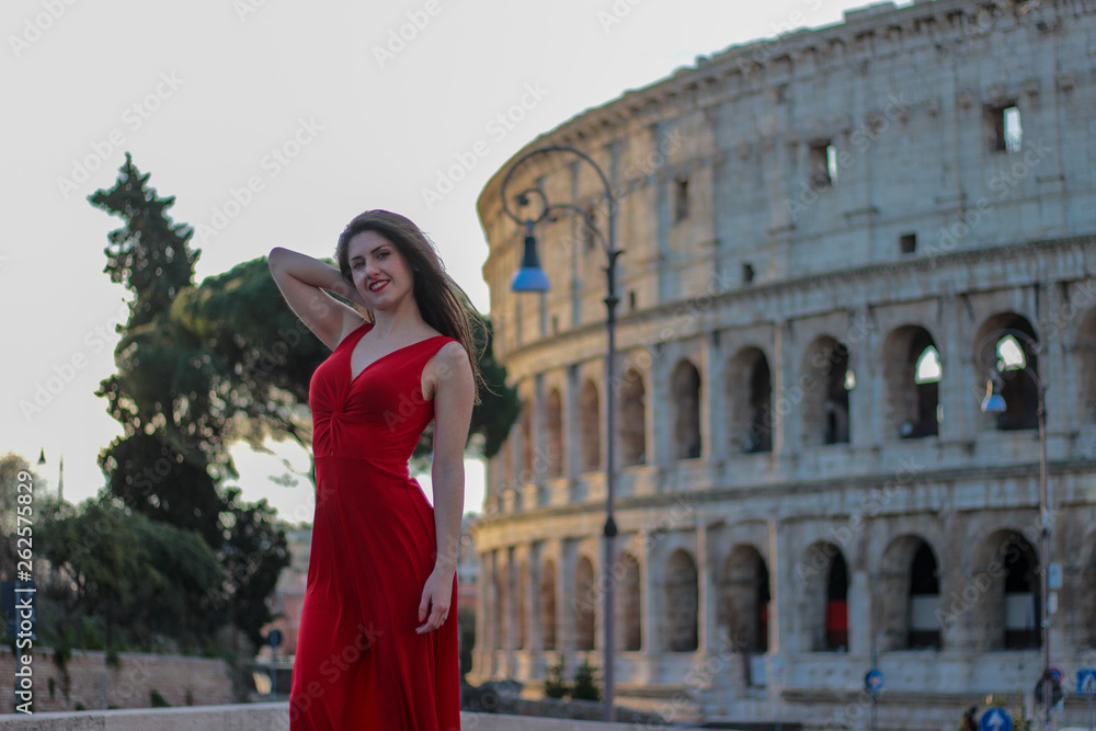 Pretty young girl in red dress in front of Colosseum, Rome, Italy. Rome symbol.