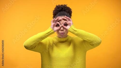 Smiling black woman making faces on yellow background, having fun, youth humor