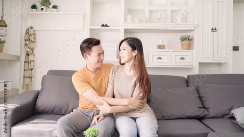 Asian couple hug together in living room at home, sweet couple enjoy love moment while lying on the sofa when relaxed at home. Lifestyle couple relax at home concept.
