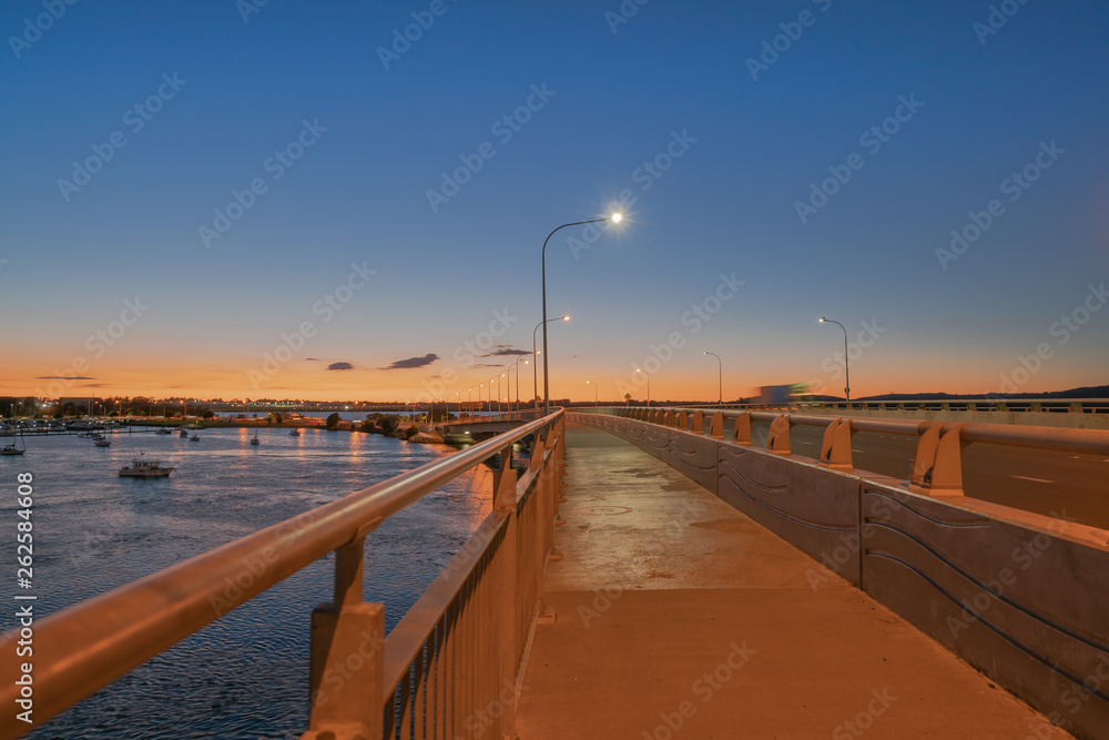 Tauranga Harbour Bridge transport route with road and pedestrian and cycle path with glow of cyclists and vehicle passing lights