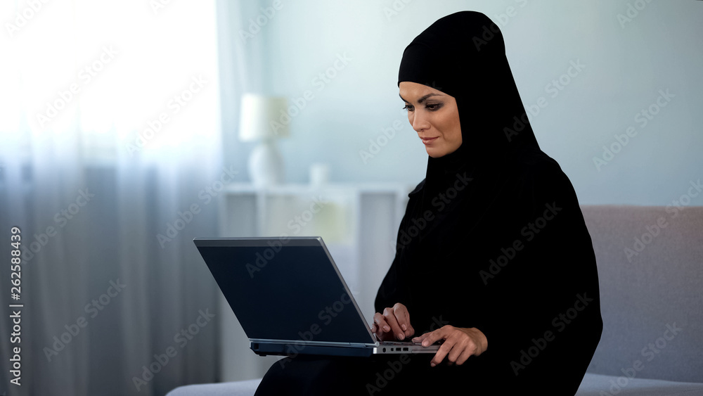 Muslim woman scrolling laptop, working at home, online education, technology Muslim woman scrolling laptop, working at home, online education, technology