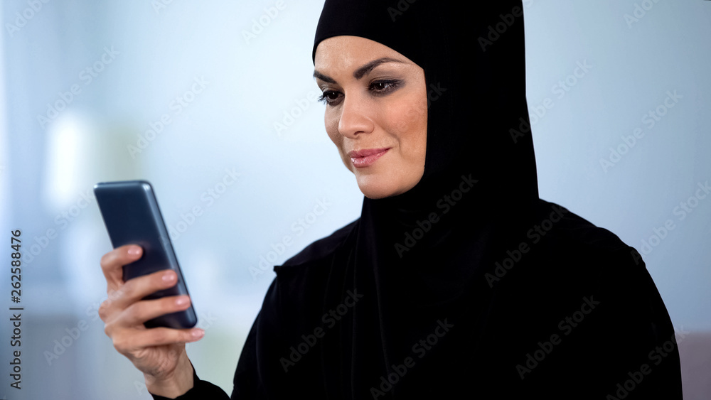 Beautiful muslim lady watching online video on smartphone, modern technology Beautiful muslim lady watching online video on smartphone, modern technology