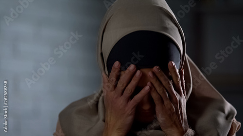 Desperate muslim woman crying  covering face with hands  family problem  shame