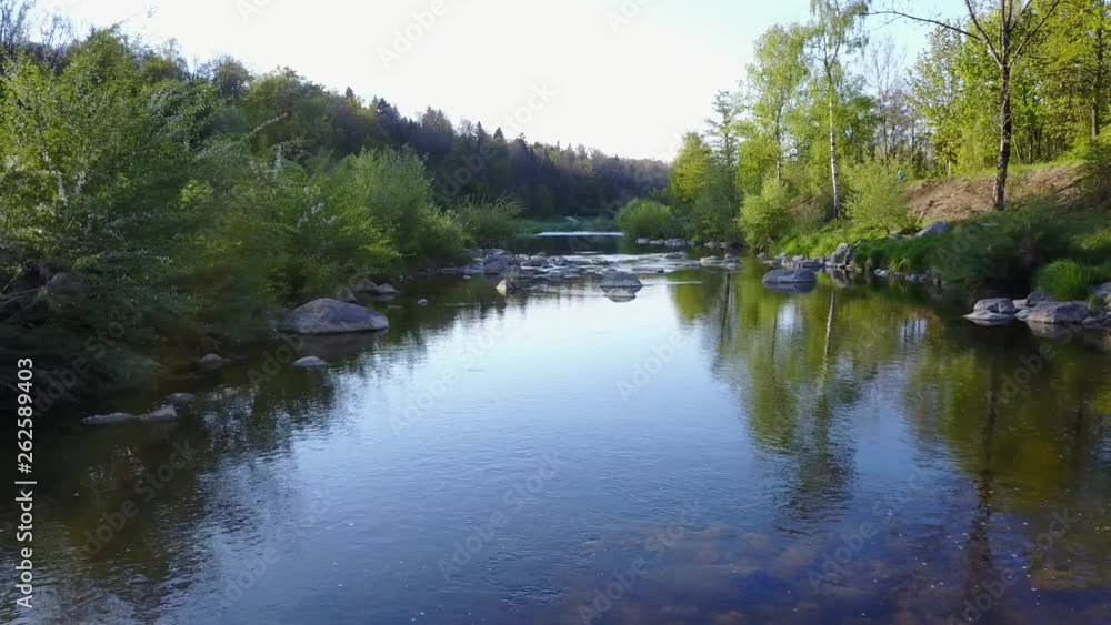 Low drone flight above river. Smooth and stabilized footage of water flowing calmly in river. Aerial view of river.