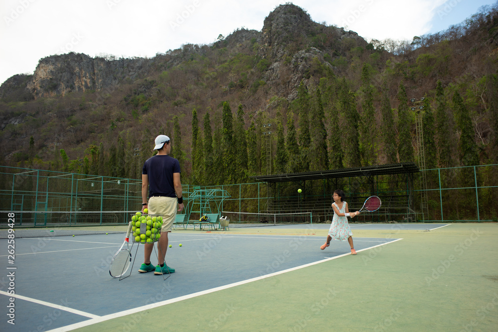 Portrait Asian girl plays tennis with her father and coach at outdoor