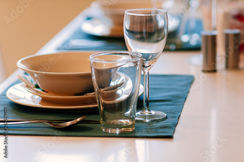 Close up dining setup with empty wine and water glasses, silver cutlery and blue napkins, decorations and items served for food, arranged by catering service in a modern restaurant, cafe