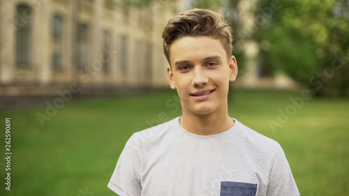 Φωτογραφία Student against university smiling at camera, foreign exchange program for teens