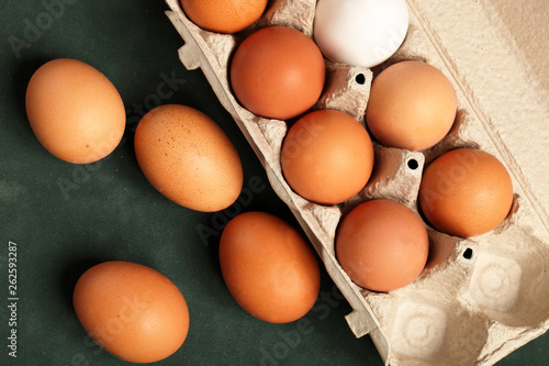 Close-up view of raw chicken eggs brown and white in box, egg white, egg brown on green background