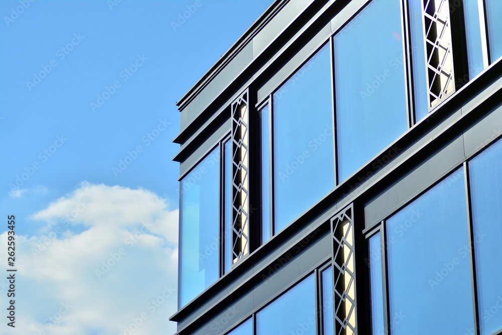 Modern office building wall made of steel and glass with blue sky Modern office building wall made of steel and glass with blue sky