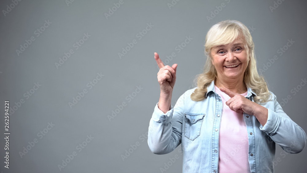 Smiling cheerful lady showing upwards gesture, place for advertisement, template Smiling cheerful lady showing upwards gesture, place for advertisement, template