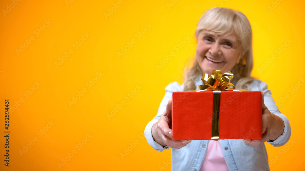 Optimistic senior lady showing present to camera, preparation for holidays Optimistic senior lady showing present to camera, preparation for holidays