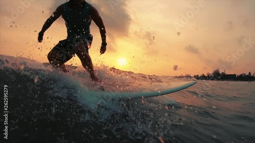 Surfer takes off with lots of splashes and rides the ocean wave at sunset. Weligama beach break in Sri Lanka