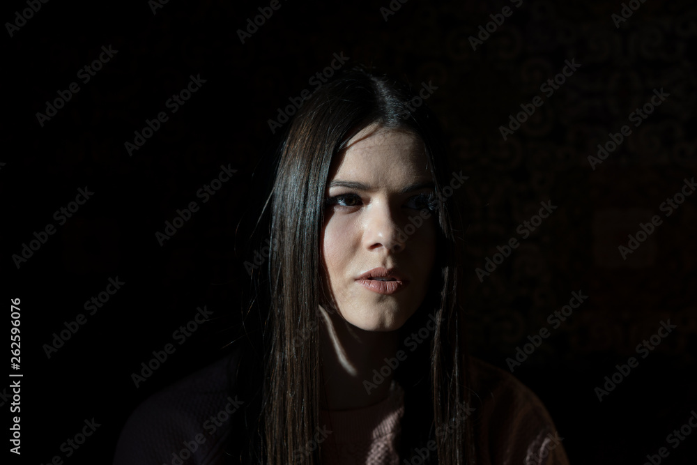 A shadow hides half the face of a girl when she sits in a cafe in the evening A shadow hides half the face of a girl when she sits in a cafe in the evening