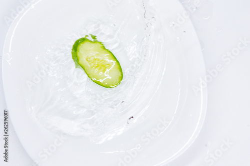 cucumber falls into a plate of water on a white background photo