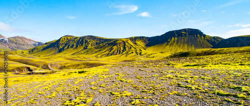 Green hills and black rocky ground of Icelandic Highlands along Laugavegur hiking trail, Iceland. Sunny summer day shot