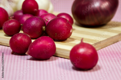 Healthy vegetables on a pink background. Fresh garlic (allium, Bulbus Allii Sativ) is a real storehouse of nutrients and trace elements. Red sweet onions (solaninum) - natural antioxidant. Red radish 