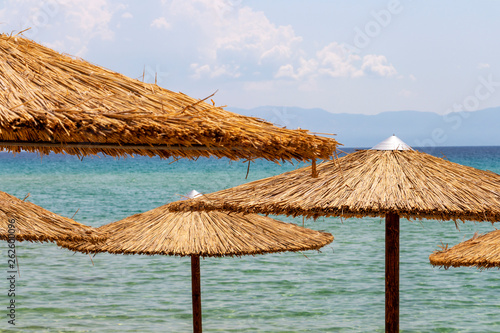 Straw beach umbrellas partial view against the Aegean Sea at Ammolofoi Beach, Kavala Region, Northern Greece