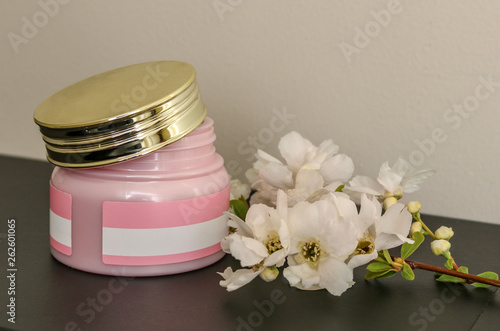 Jar of cosmetic cream and flower