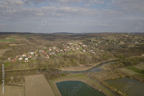 Panorama from a bird's eye view. Central Europe: The Polish village is located among the green hills and river. Temperate climate. Flight drones or quadrocopter. Urbanization of the landscape