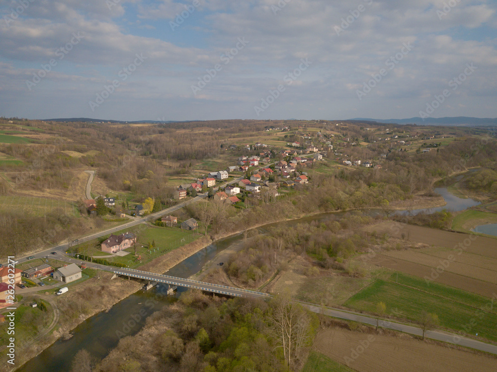 Panorama from a bird's eye view. Central Europe: The Polish village is located among the green hills and river. Temperate climate. Flight drones or quadrocopter. Urbanization of the landscape