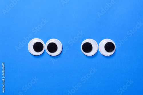 Картината върху платно Googly eyes: Two pair strabismus and squint mad googly eyes next to each other on a blue background