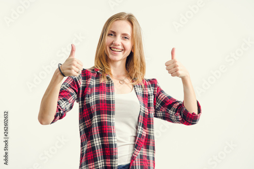 Schilderij op canvas Like! Beautiful happy young woman shows thumbs up sign very well standing on a light background