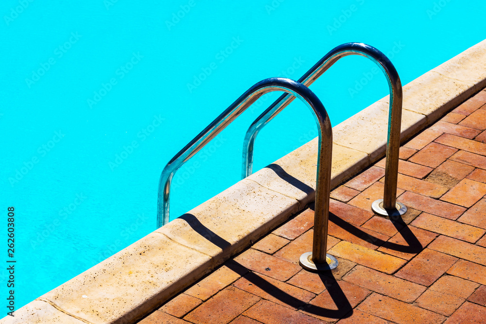 Grab bars ladder in the blue swimming pool Grab bars ladder in the blue swimming pool