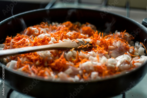 Cooking for soup, chopped carrots and onions are fried in a pan
