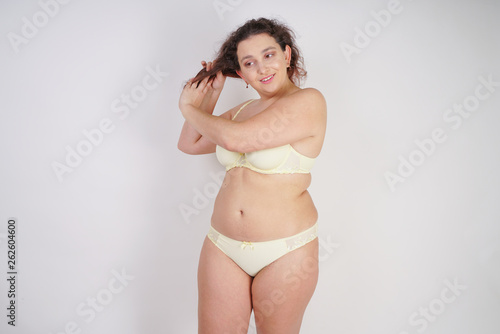 Canvas Print cute chubby woman in yellow fashion lingerie touching her hair on white backgrou