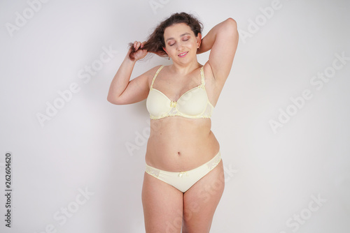 Cuadro en lienzo cute chubby woman in yellow fashion lingerie touching her hair on white backgrou