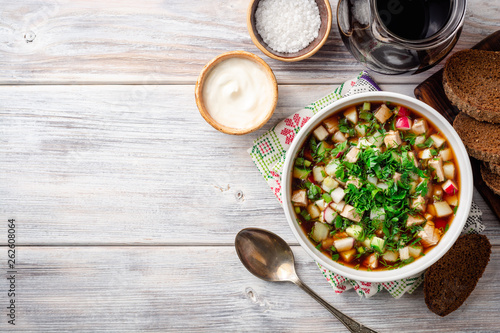Traditional Russian summer cold soup okroshka with kvass in bowl on wooden background. Top view. Copy space. photo