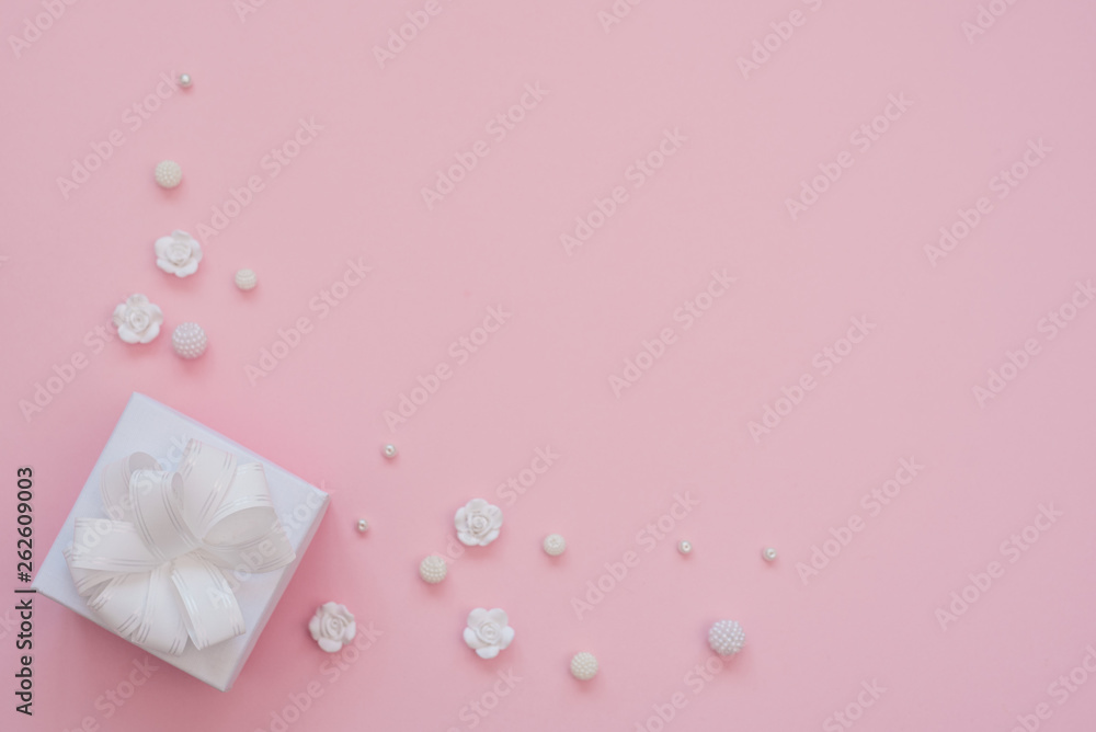 Close up shot of small white gift wrapped with white ribbon on pink background. Minimal concept. Flat lay. Top view. Close up shot of small white gift wrapped with white ribbon on pink background. Minimal concept. Flat lay. Top view.