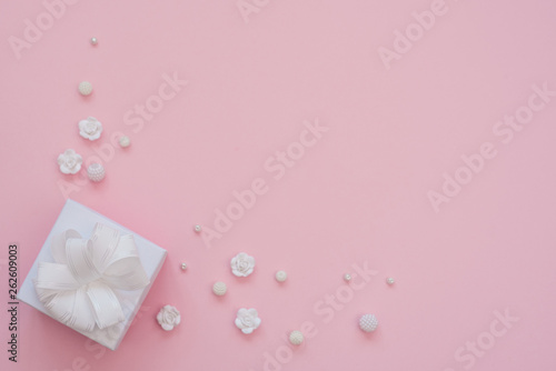 Close up shot of small white gift wrapped with white ribbon on pink background. Minimal concept. Flat lay. Top view. © Vita