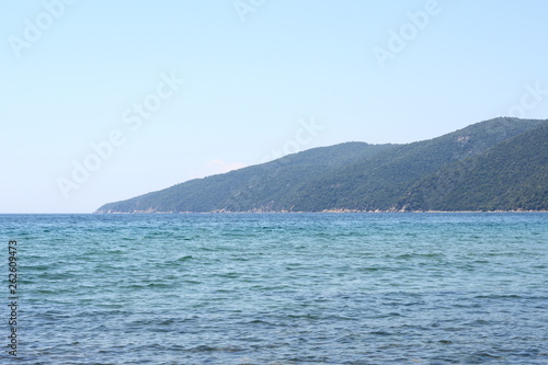Beautiful minimalistic seascape of calm sea, sandy beach, blue sky, Greece. Horizontal. © Sanja
