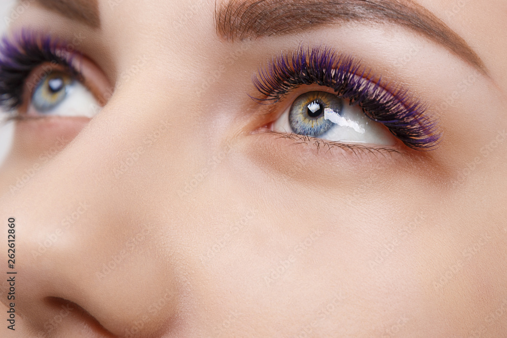 Eyelash Extension Procedure. Woman Eye with Long Blue Eyelashes. Ombre effect. Close up, selective focus. Eyelash Extension Procedure. Woman Eye with Long Blue Eyelashes. Ombre effect. Close up, selective focus.