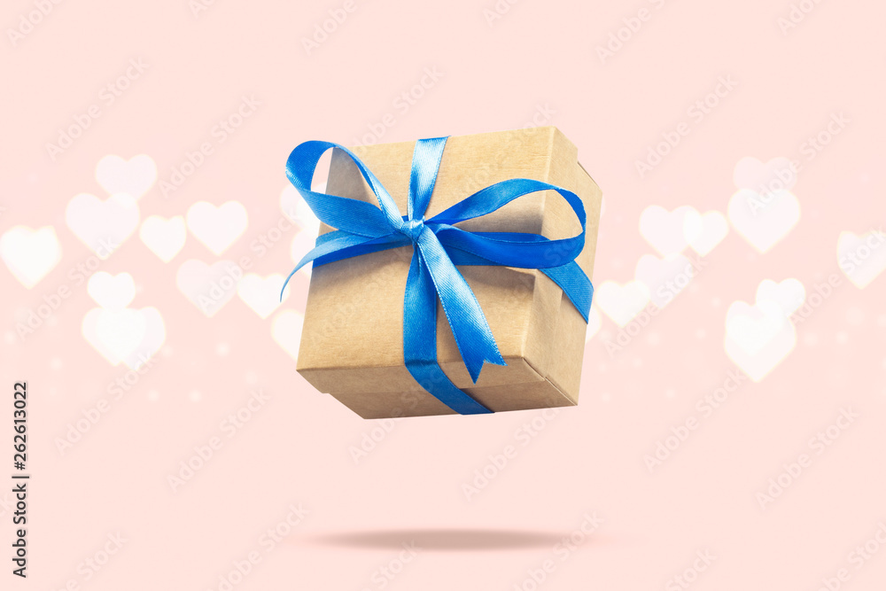 Flying gift box on a light pink background with heart shaped bokeh. Holiday concept, gift, sale, wedding and birthday. Flying gift box on a light pink background with heart shaped bokeh. Holiday concept, gift, sale, wedding and birthday.