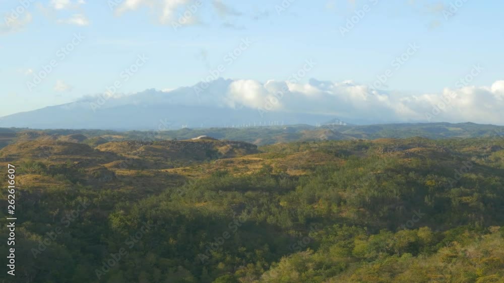 View of Costa Rican landscape with volcano in the background and jungle in the foreground. Windmills on the horizon. View of Costa Rican landscape with volcano in the background and jungle in the foreground. Windmills on the horizon.