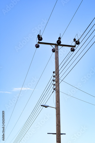 Low angle view of wooden electricity pylon against clear blue sky .