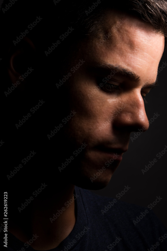 man side face looking down with a dark backgroung