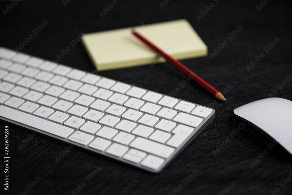 textured black board with a pencil on a paper, a keyboard and a mouse in a workplace scenario textured black board with a pencil on a paper, a keyboard and a mouse in a workplace scenario